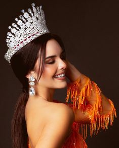 a woman wearing a tiara and smiling at the camera with her hand on her head