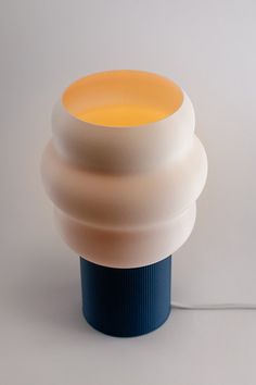 a white and blue lamp sitting on top of a table next to a light bulb