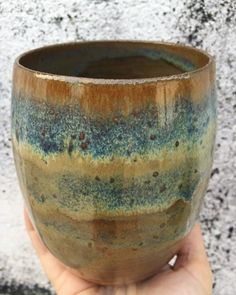 a hand holding a brown and blue cup