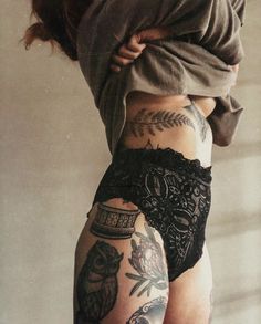 a woman with tattoos on her back and legs is holding onto another person's leg