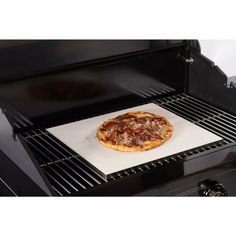 a pizza sitting on top of a white paper under an oven grilling pan in front of it