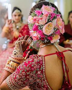 the back of a woman's head with pink flowers in her hair and jewelry