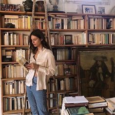 a woman standing in front of a book shelf filled with books