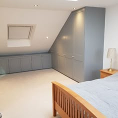 a bedroom with a bed, dressers and storage units in the attic area on the second floor