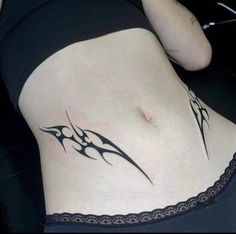 a woman's stomach with a tattoo design on her belly and the bottom part of her lower back