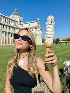 a woman holding an ice cream cone in front of the leaning tower of pisa, italy