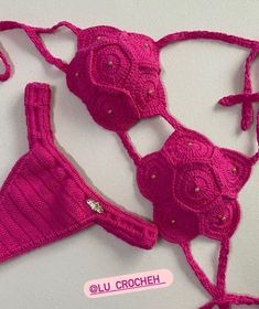 two pieces of pink crochet bras and panties on a white table top