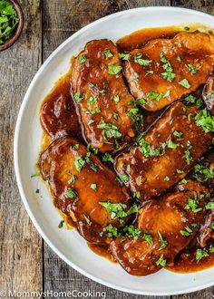 a white plate topped with meat covered in sauce and garnished with parsley