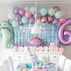 a birthday party with mermaid decorations and balloons on the wall, including an ocean theme