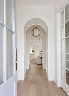 the hallway is lined with white walls and wood flooring, along with glass doors