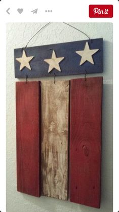 an american flag made out of wooden planks hanging on a wall with three stars