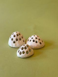 three white ceramic rocks sitting on top of a green surface with holes in the middle