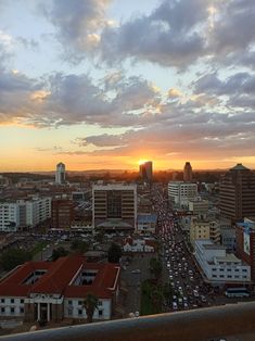 the sun is setting over a city with tall buildings and cars on it's sides