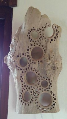 a piece of wood that has holes and holes in the middle of it, hanging on a wall