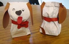 two paper bags with dogs on them sitting on top of a wooden table next to each other