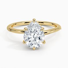 a yellow gold engagement ring with a pear shaped diamond in the center, on a white background