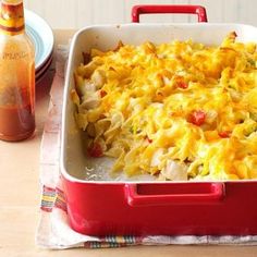 a casserole dish with chicken and vegetables in it next to a bottle of orange juice