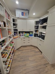 a kitchen with white cabinets and shelves filled with food