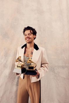 a man holding two golden trophies in his hands