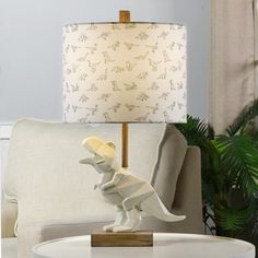 a table with a lamp and a dinosaur figurine on it