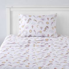 a white bed with unicorns and rainbows on the sheets, pillow cases and duvet covers