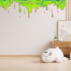 a white elephant sitting on top of a wooden floor next to a wall with dripping paint