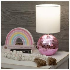 a pink disco ball lamp sitting on top of a table next to a stack of books