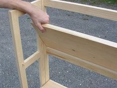 a person is holding onto the side of a wooden bench with one hand on it