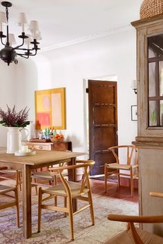 a dining room table and chairs in front of a doorway with a painting on the wall