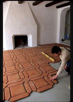 a man laying bricks on the ground in front of a fireplace