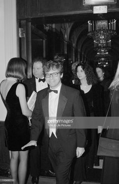 a man in a tuxedo and bow tie is walking down the hall with other people