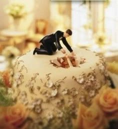 two figurines sitting on top of a wedding cake with flowers in the background