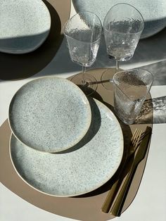 there are three plates on the table with silverware and glasses next to each other