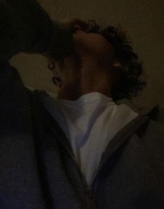 a person with curly hair wearing a hoodie looking up at something on the screen