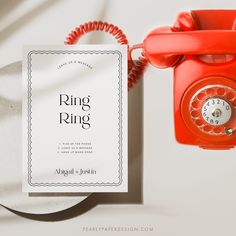 an orange phone sitting next to a white paper with the word ring ring on it