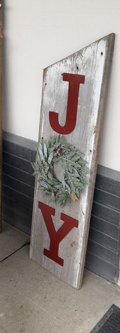 a wooden sign that says joy with a wreath on the front and side of it