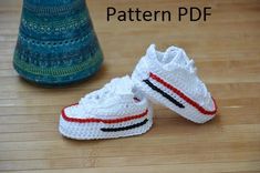 two crocheted shoes sitting on top of a wooden floor next to a vase