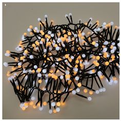 a pile of black and white string lights on a gray surface with one light turned yellow