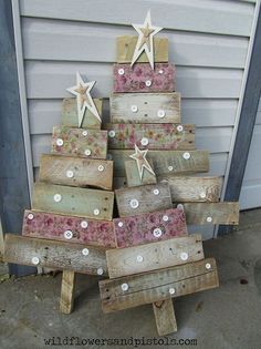 a christmas tree made out of old wooden pallets with star decorations on top, sitting in front of a house