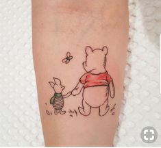 a small winnie the pooh and pig tattoo on the right leg, with a butterfly flying over it