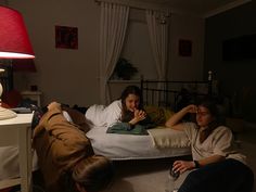 two women sitting on a bed in the dark, one is holding her hand up to her mouth