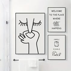 a white bathroom with black and white artwork on the wall