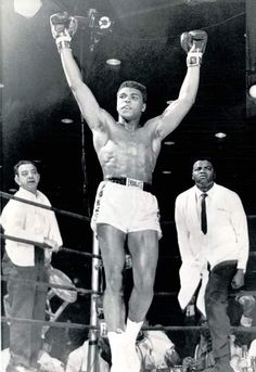 a man standing on top of a boxing ring holding his hands up in the air