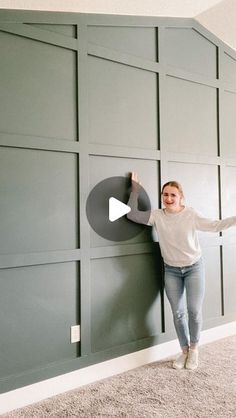 a woman standing next to a wall with a video player on it