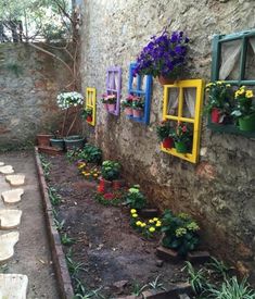 an outdoor area with flowers and plants on the side of the building, along with potted plants