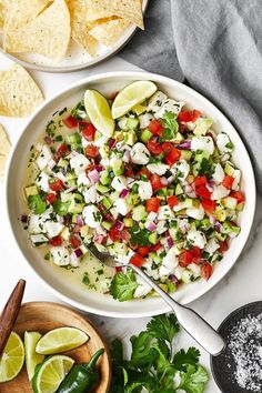 a white bowl filled with cucumber and red onion salad next to tortilla chips