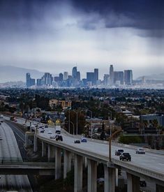 an overpass with cars driving on it and the city in the background