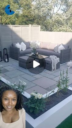 a woman standing in front of a patio with furniture and flowers on the ground next to it