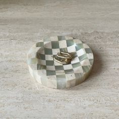 a ring dish sitting on top of a marble counter next to a white wall and floor