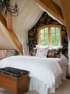 a bedroom with a bed, chair and window in the atticed room that has floral wallpaper on the walls